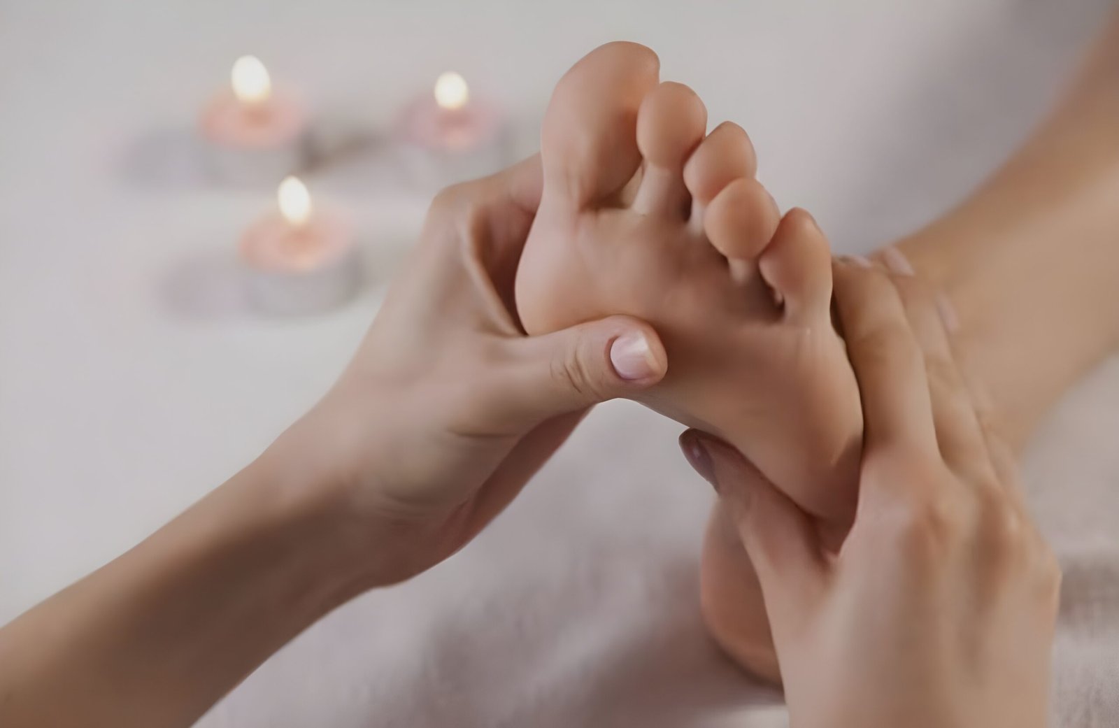primo piano di due mani che eseguono un massaggio di riflessologia plantare sulla pianta di un piede